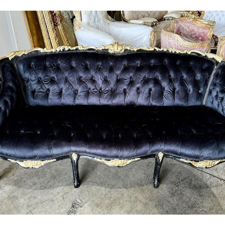 a black and gold couch sitting on top of a cement floor next to a mirror