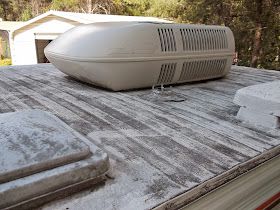 an air conditioner sitting on top of the roof of a house in front of some trees