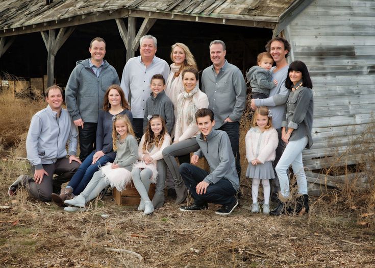 a large family poses for a photo in front of an old barn