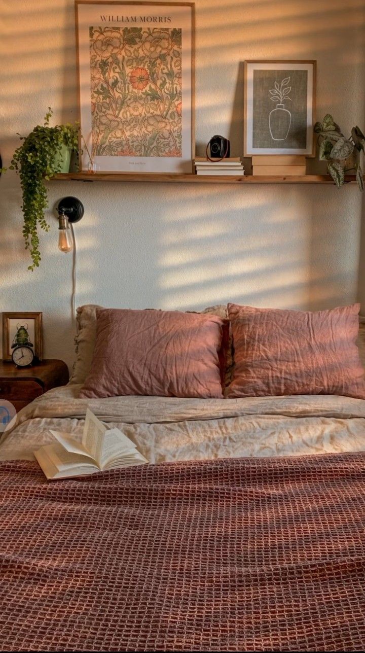 the bed is made up with pink sheets and pillows, along with pictures on the wall