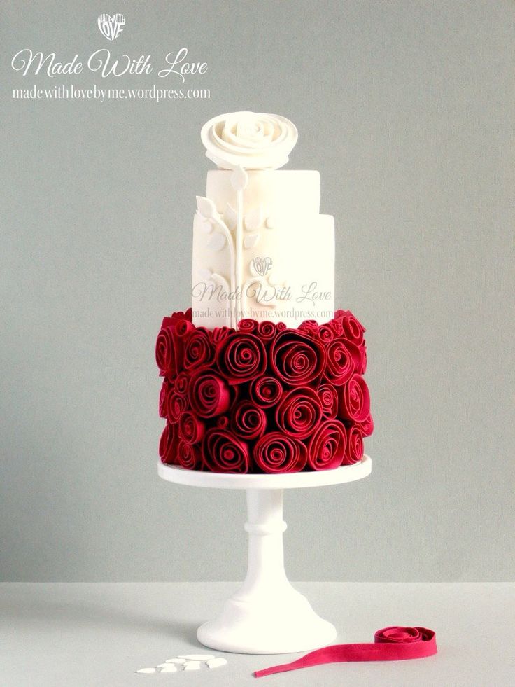 a white and red wedding cake with roses on it