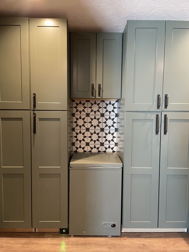 a kitchen with gray cabinets and a white dishwasher in the center is shown