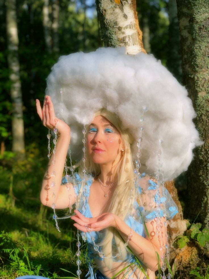 a woman sitting on the ground with a large cloud over her head and hands in front of her face