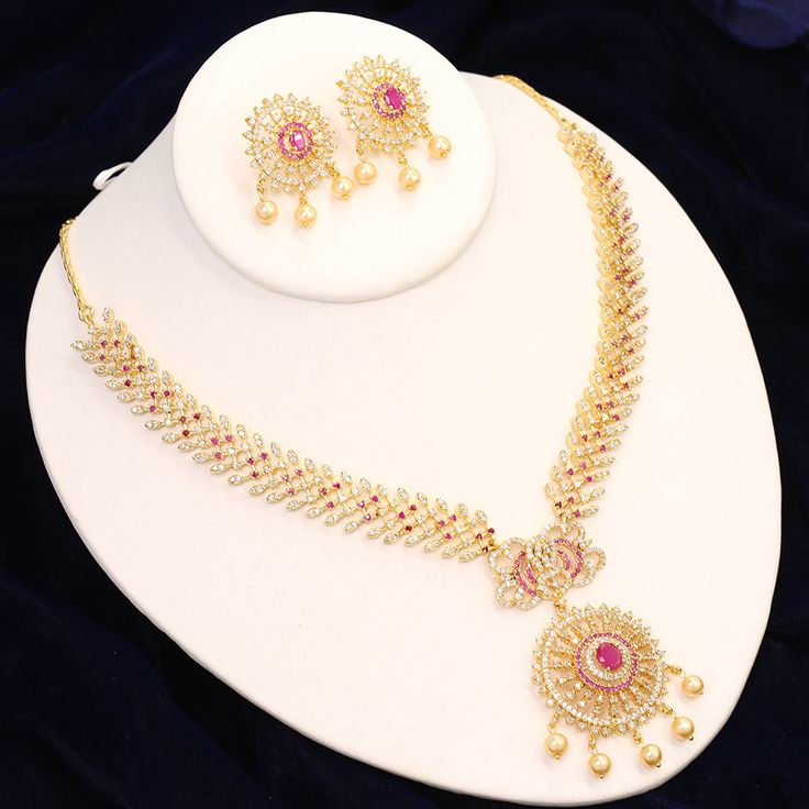 "Traditional party wear American Diamond fashion necklace set studded with white, emerald and Ruby cubic zirconia stones . The necklace set has matching earrings. Necklace Length: 5\" Inches each side + Length of Extender is 4 inches each side Pendant Length: 2.5 inches Length of Earring is 1.5 inches approx. Best suitable for Party Wear / Fashion Wear for Any Occasion. Care Instructions: We recommend avoiding direct exposure to fragrances. Packed in A Neat Box, Ideal for Gifting" Diwali Celebration Jewelry With Cubic Zirconia, Festive Cubic Zirconia Jewelry Sets, American Diamond Jewelry Sets For Diwali Celebration, Diwali Cubic Zirconia Jewelry, Cubic Zirconia Jewelry For Diwali Gift, Formal Cubic Zirconia Jewelry For Diwali, Elegant American Diamond Jewelry Sets For Festivals, Elegant Cubic Zirconia Jewelry Sets For Festivals, Cubic Zirconia Jewelry Sets For Festivals Gift