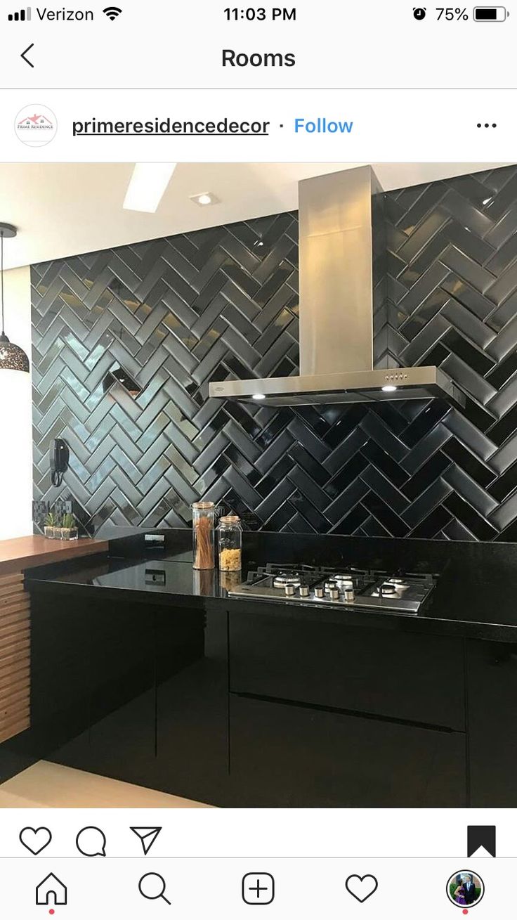 a kitchen with black tiles on the wall and counter tops, along with an oven