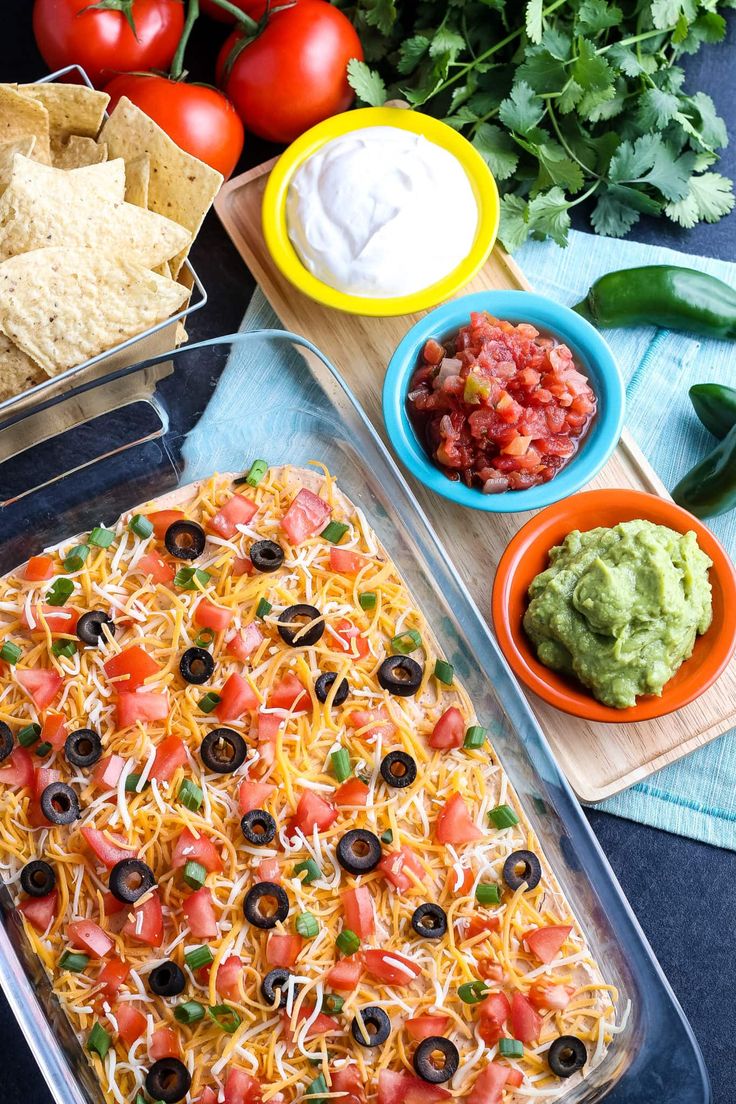 a casserole dish with tortilla chips, salsa and guacamole