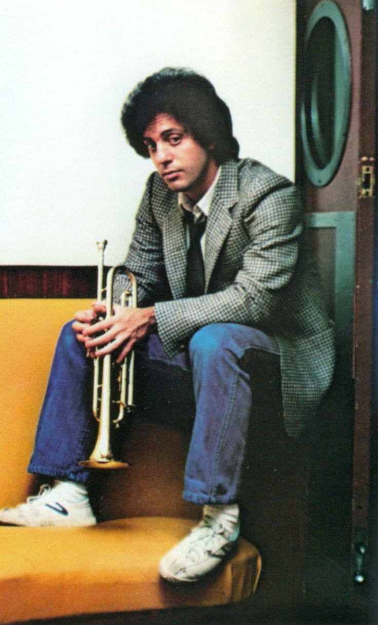 a man sitting on top of a yellow couch holding a trumpet in his hand and looking at the camera