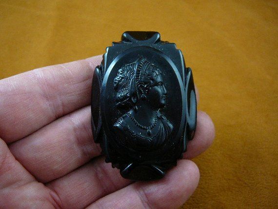 (Internal #C-1557)  Excellent, black mourning cameo of a Woman with tiara (matching Bakelite cameo to setting), oval shape with ridge design, 2-1/2” long x 1-3/4” wide, new clasp pin on reverse.Both settings and the cameo are VINTAGE, Circa 1920's. Settings are bakelite, cameo materials are as indicated.WE SHIP WORLDWIDE! Other accepted payment: Credit card (Mastercard/Visa/Discover) inquire for details. Elegant Black Cameo Brooches, Antique Black Brooch For Wedding, Antique Black Brooches For Formal Occasions, Antique Black Wedding Brooch, Antique Black Wedding Brooches, Black Cameo Jewelry For Collectors, Collectible Black Cameo Jewelry, Victorian Black Cameo Brooches, Wood Branding