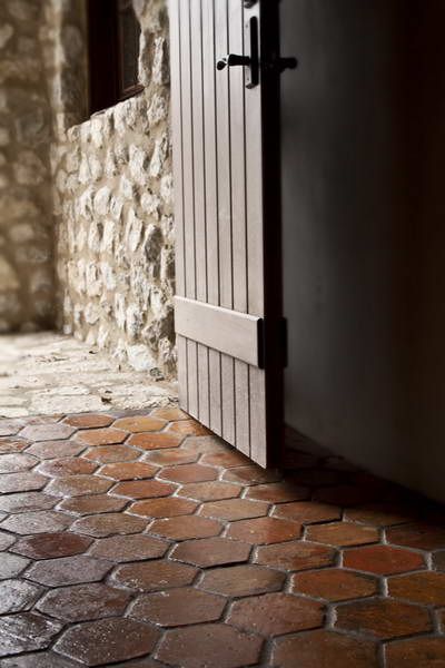 an open door is shown in front of a stone wall and brick floored area