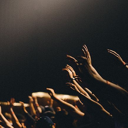 a crowd of people raising their hands in the air