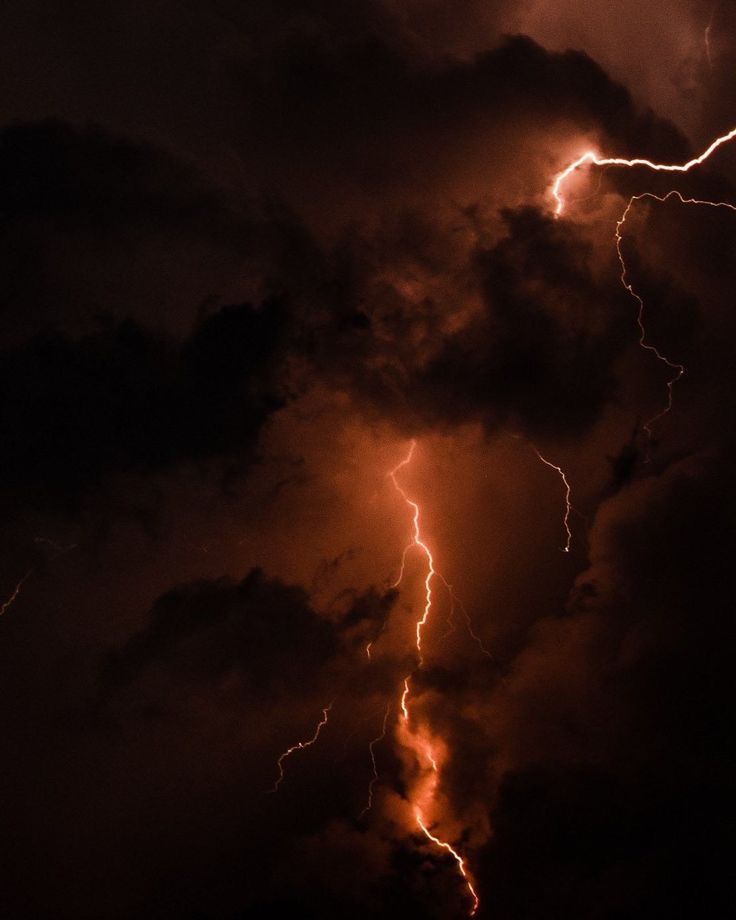 a lightning bolt is seen in the sky above some dark clouds at night with orange and yellow lightening