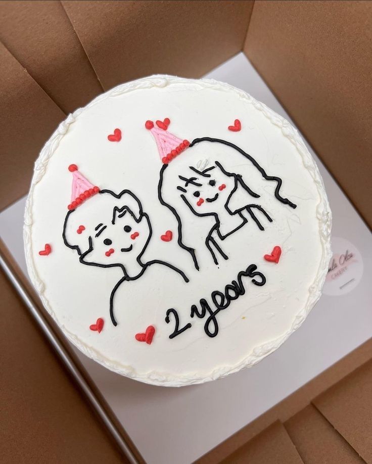 a birthday cake with two dogs and hearts on the top is in a cardboard box