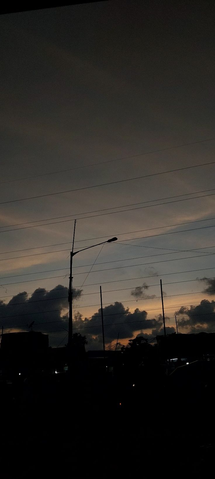 the sky is very dark and cloudy at night, with power lines in the foreground