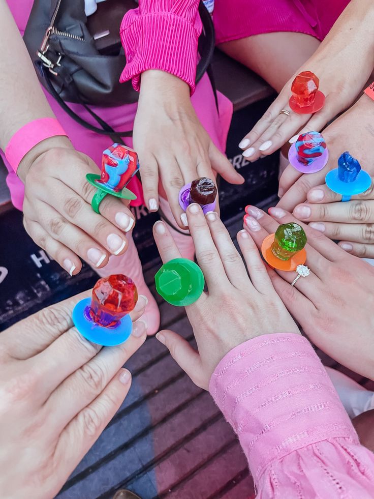 many people are holding their hands together with colorful rings on each hand and buttons in the middle