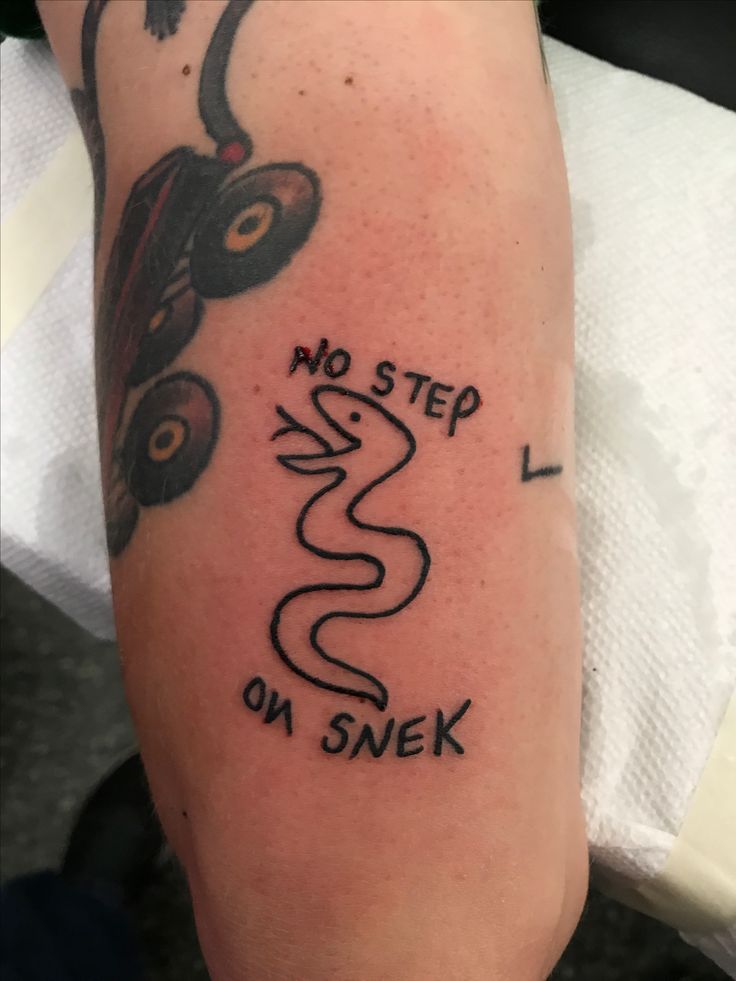 a person with a tattoo on their arm that says, no step i'm on snek