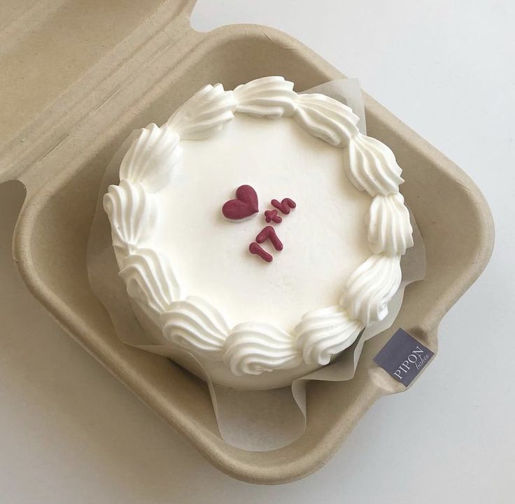 a white cake with two hearts on it in a box, ready to be eaten