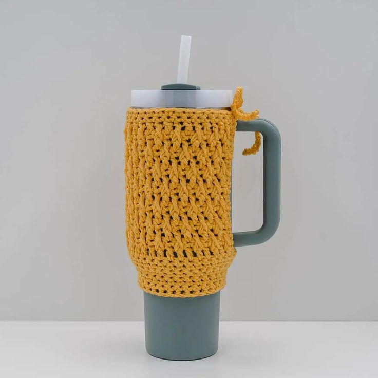 a crocheted coffee mug cozys up with a straw in the cup holder