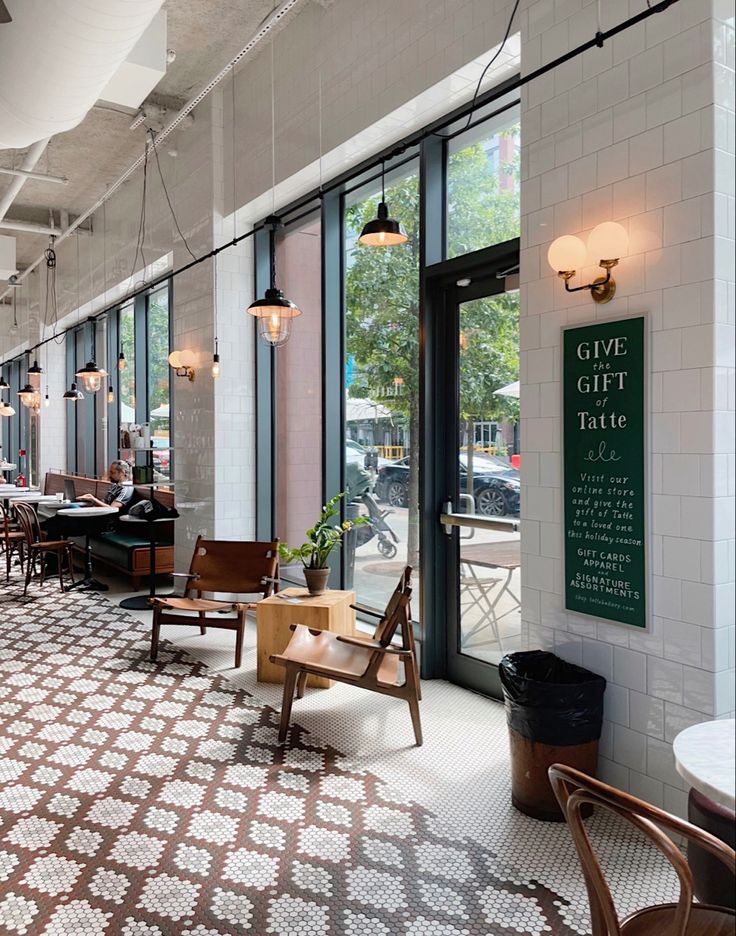 an empty restaurant with tables and chairs in front of large glass windows that look out onto the street