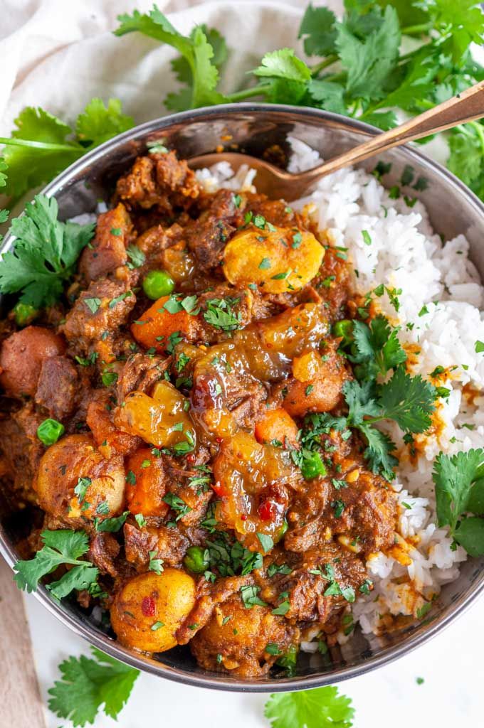 a bowl filled with rice, meat and veggies next to cilantro