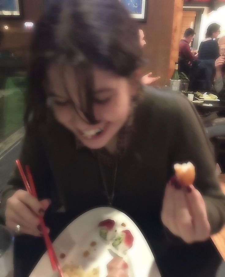 a woman eating sushi with chopsticks at a restaurant