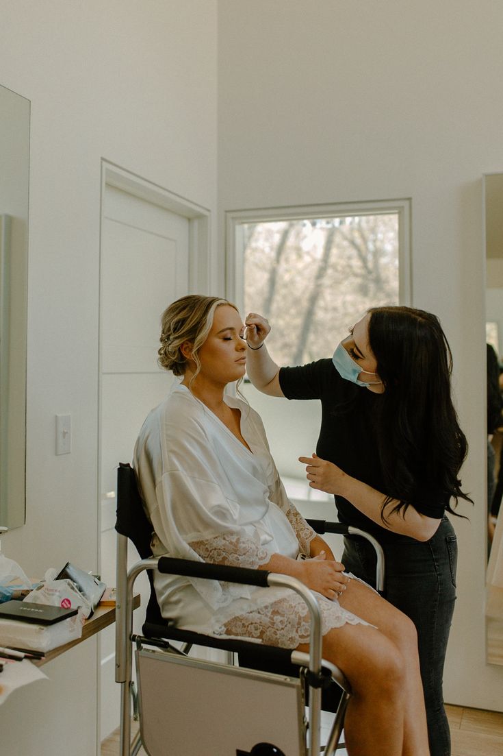 a woman getting her make up done by another woman in a chair at a hair salon