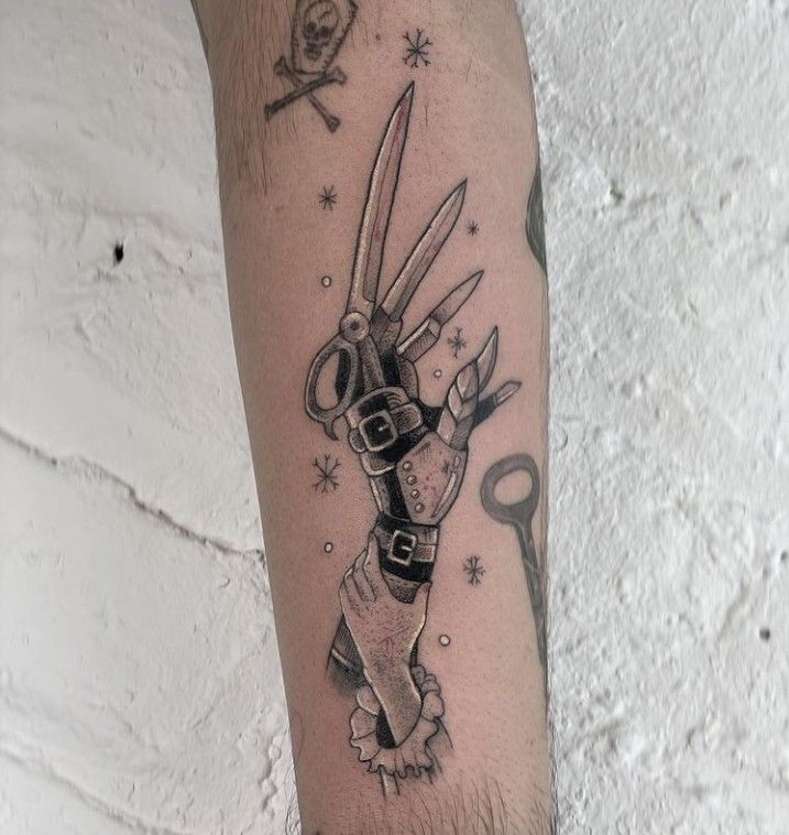 a tattoo on the arm of a man with scissors