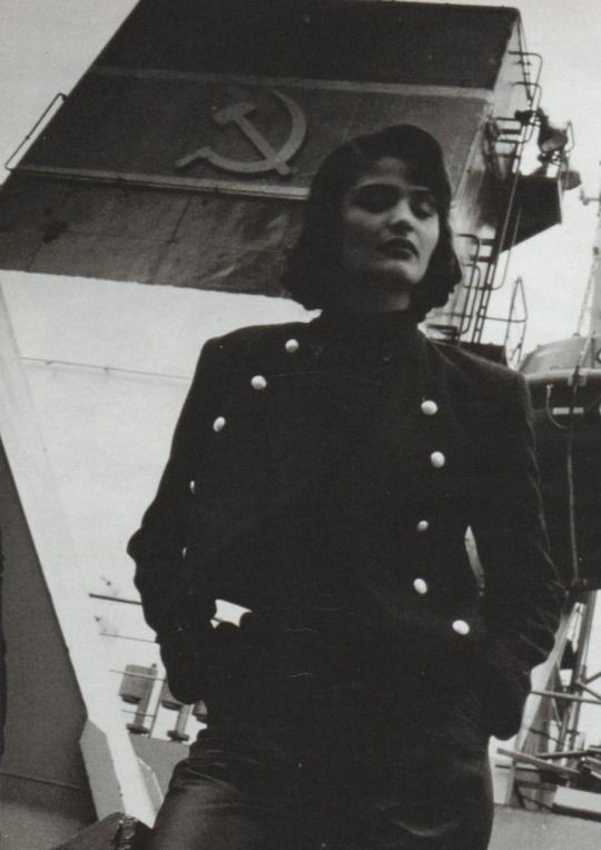 an old photo of a woman in uniform standing on the deck of a ship, looking off into the distance