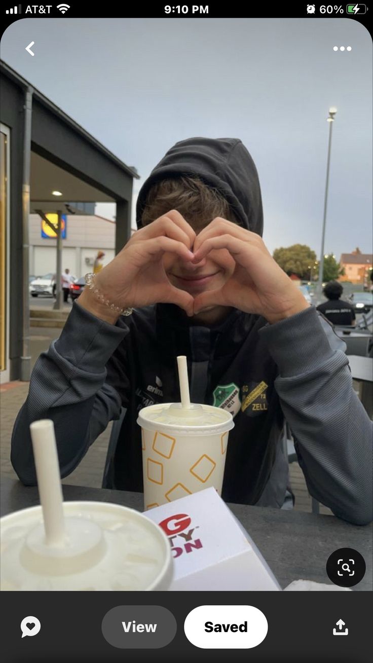 a man sitting at a table with a drink in front of him and his hands covering his face