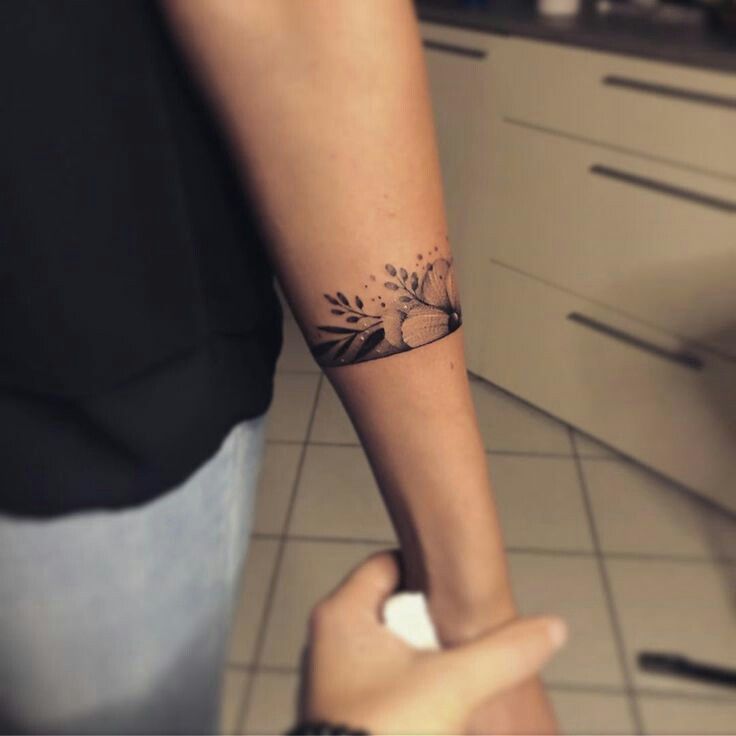 a woman with a tattoo on her arm holding the hand of another person's wrist