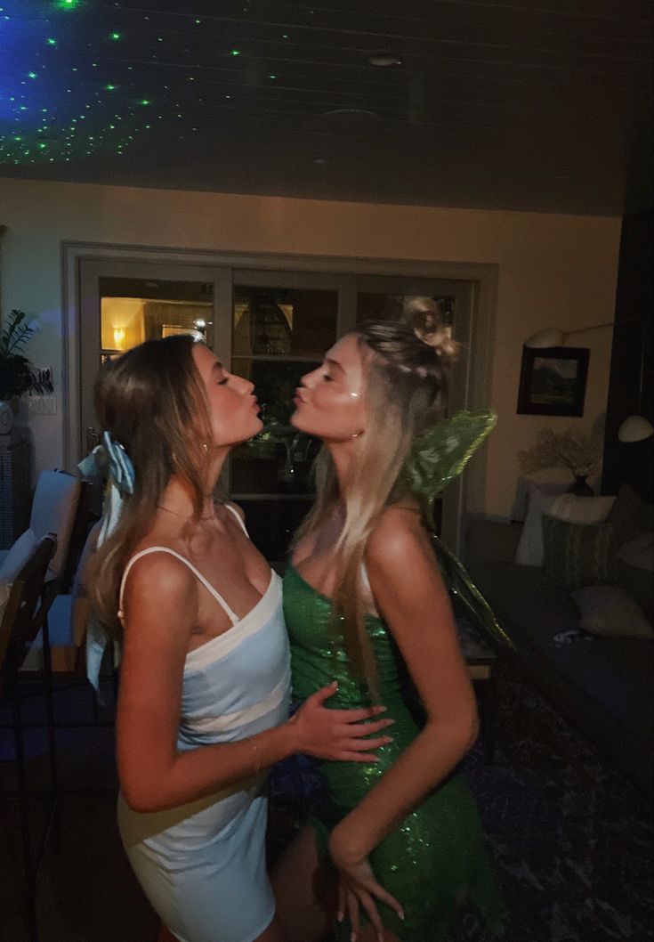 two beautiful young women standing next to each other in front of a table with lights on it