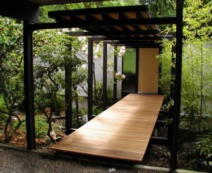 a wooden platform in the middle of a garden with trees and bushes behind it on a phone screen