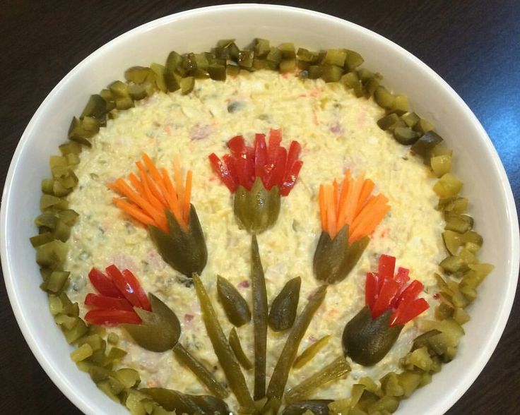 a white bowl filled with food and flowers on top of a wooden table next to a knife