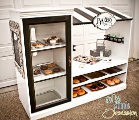 a bakery display case with cupcakes and pastries in the front, including donuts