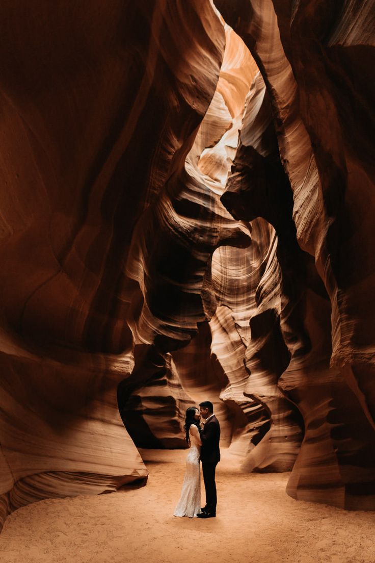 a bride and groom standing in the middle of a slot at antelope canyon