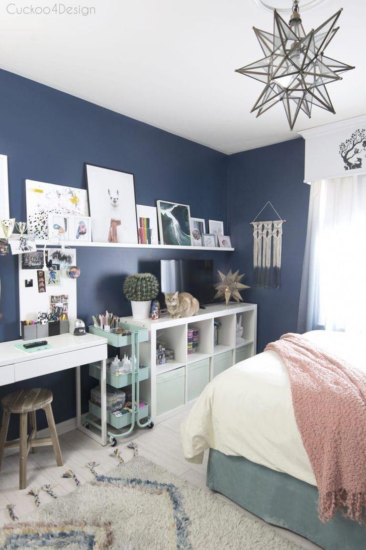 a bedroom with blue walls, white furniture and pictures on the wall above the bed