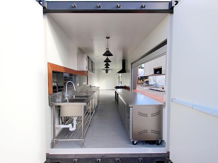 an open door leading to a kitchen with stainless steel appliances and sinks on the outside