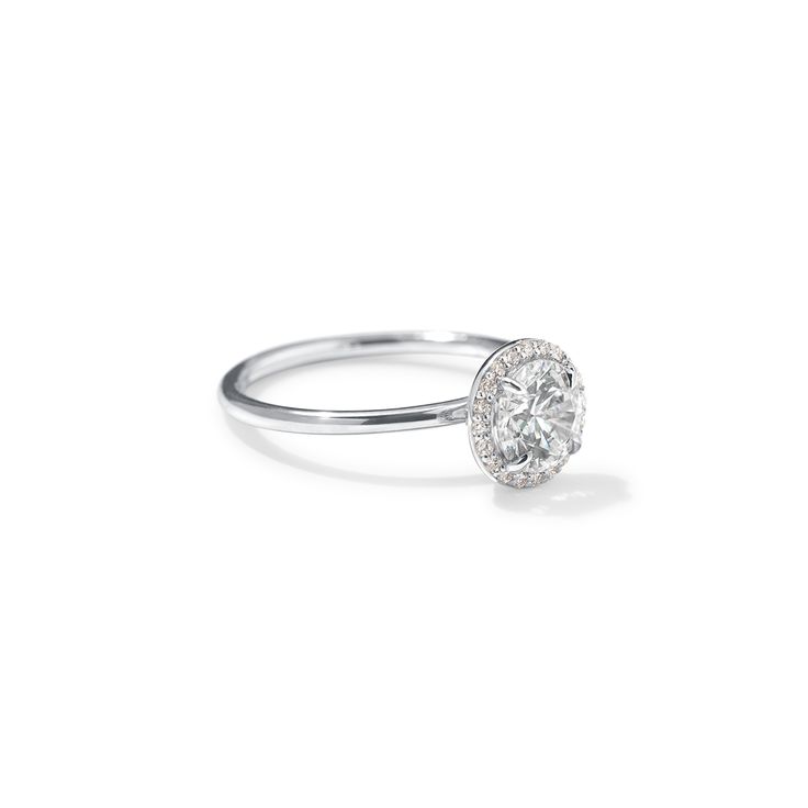 a white gold ring with a round diamond in the center, on a white background