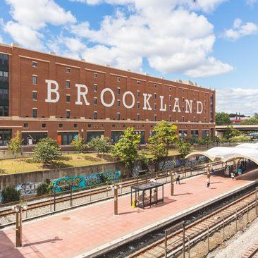 an old brick building with the word brookland written on it's side in front of train tracks