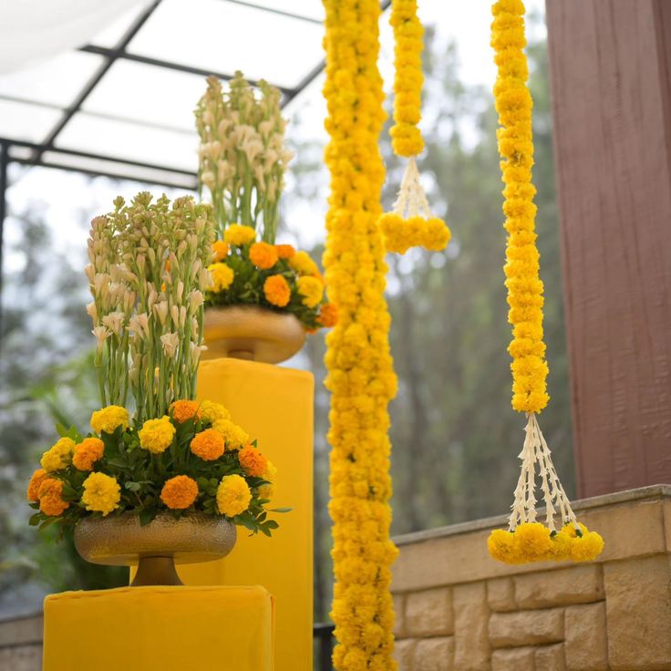 yellow and white flowers are hanging from the ceiling