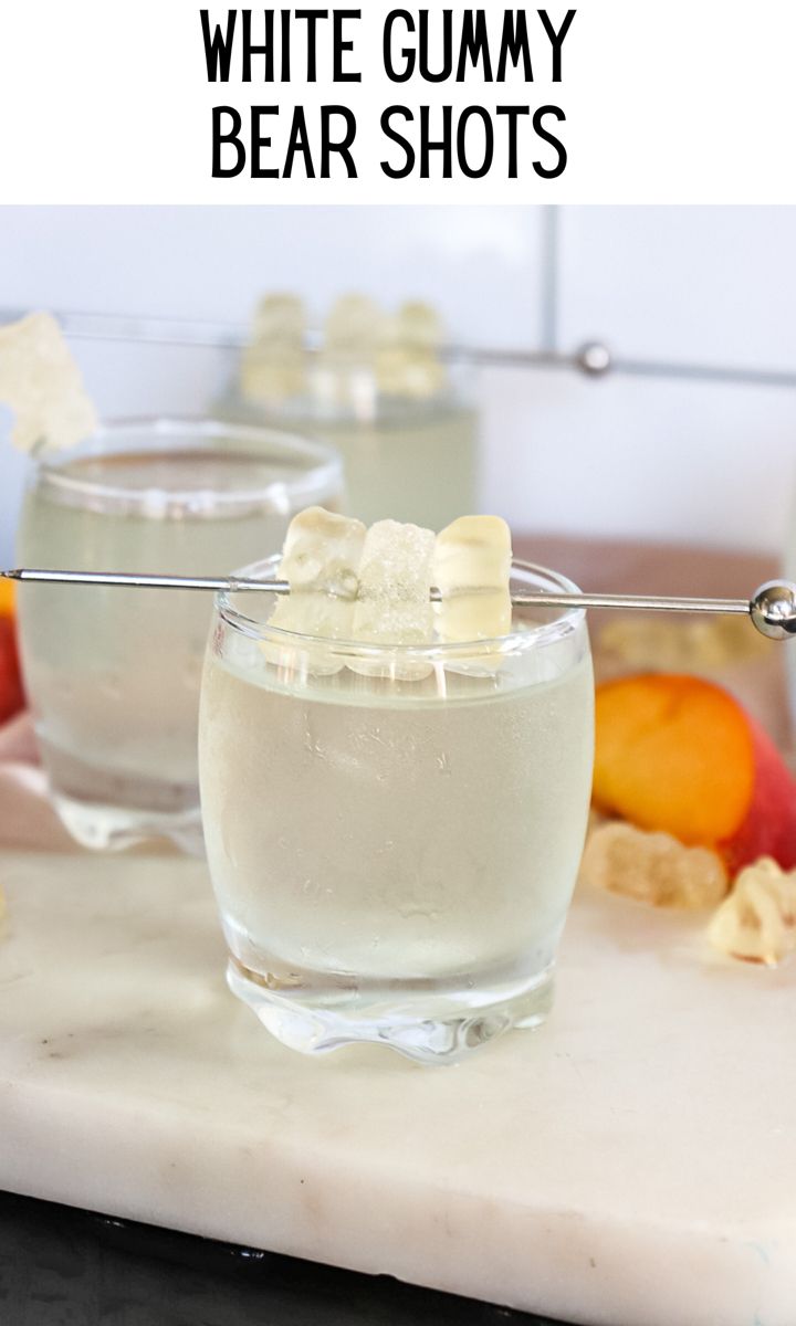 two glasses filled with ice and fruit on a counter top next to some spoons