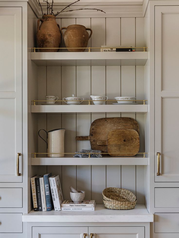 the shelves in this kitchen are filled with books and other items, including bowls and utensils