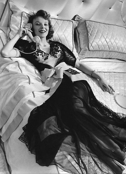 a woman laying on top of a bed in a black and white photo