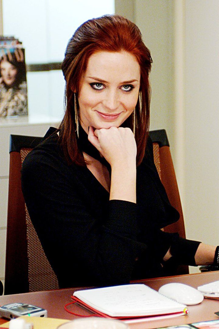 a woman sitting in an office chair with her hand on her chin and looking at the camera