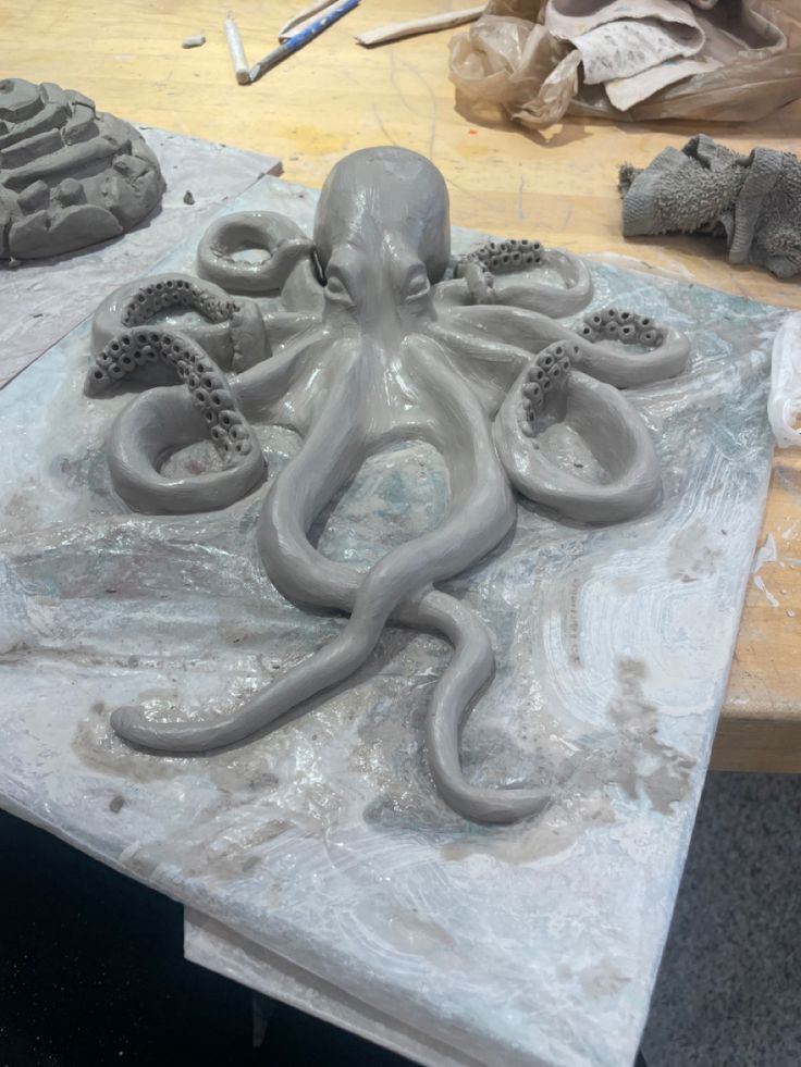 an octopus sculpture sitting on top of a table next to other clay sculptures and tools