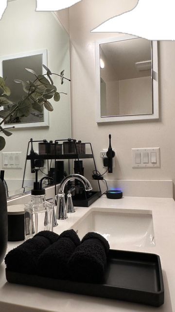 a bathroom sink with black towels on it and a plant in the corner next to it