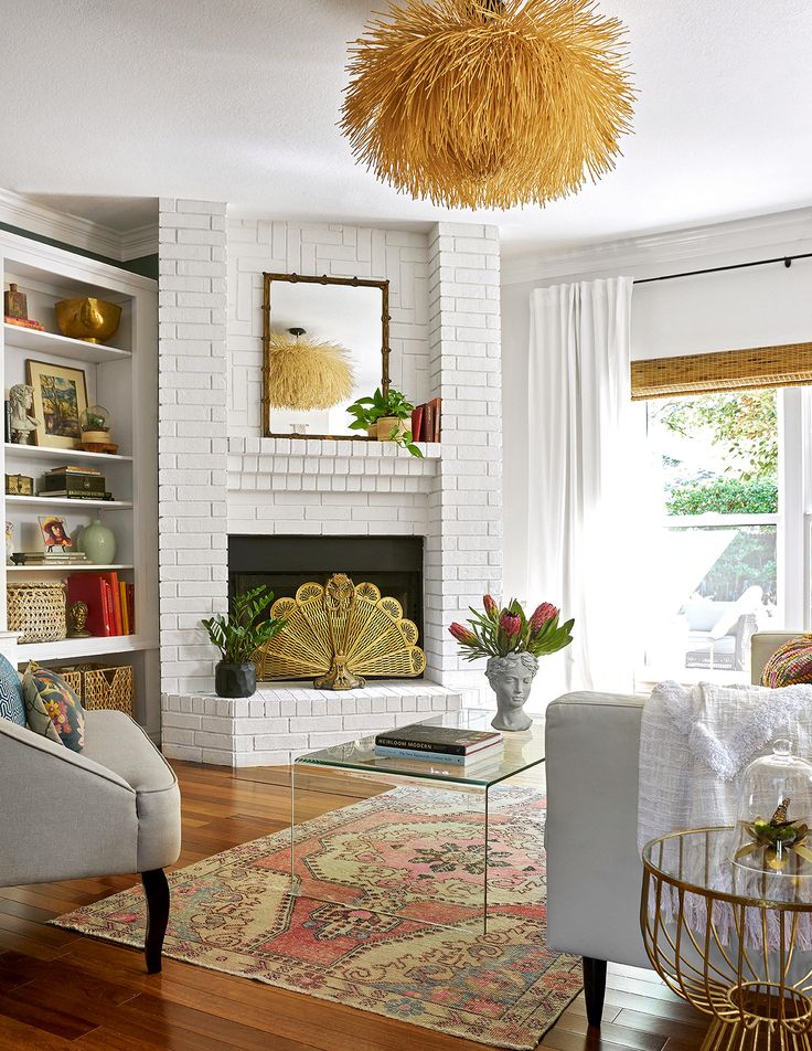 a living room filled with furniture and a fire place in front of a white brick wall