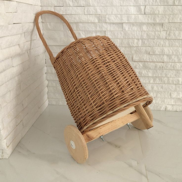 a wicker basket sitting on top of a wooden wheelbarrow next to a brick wall