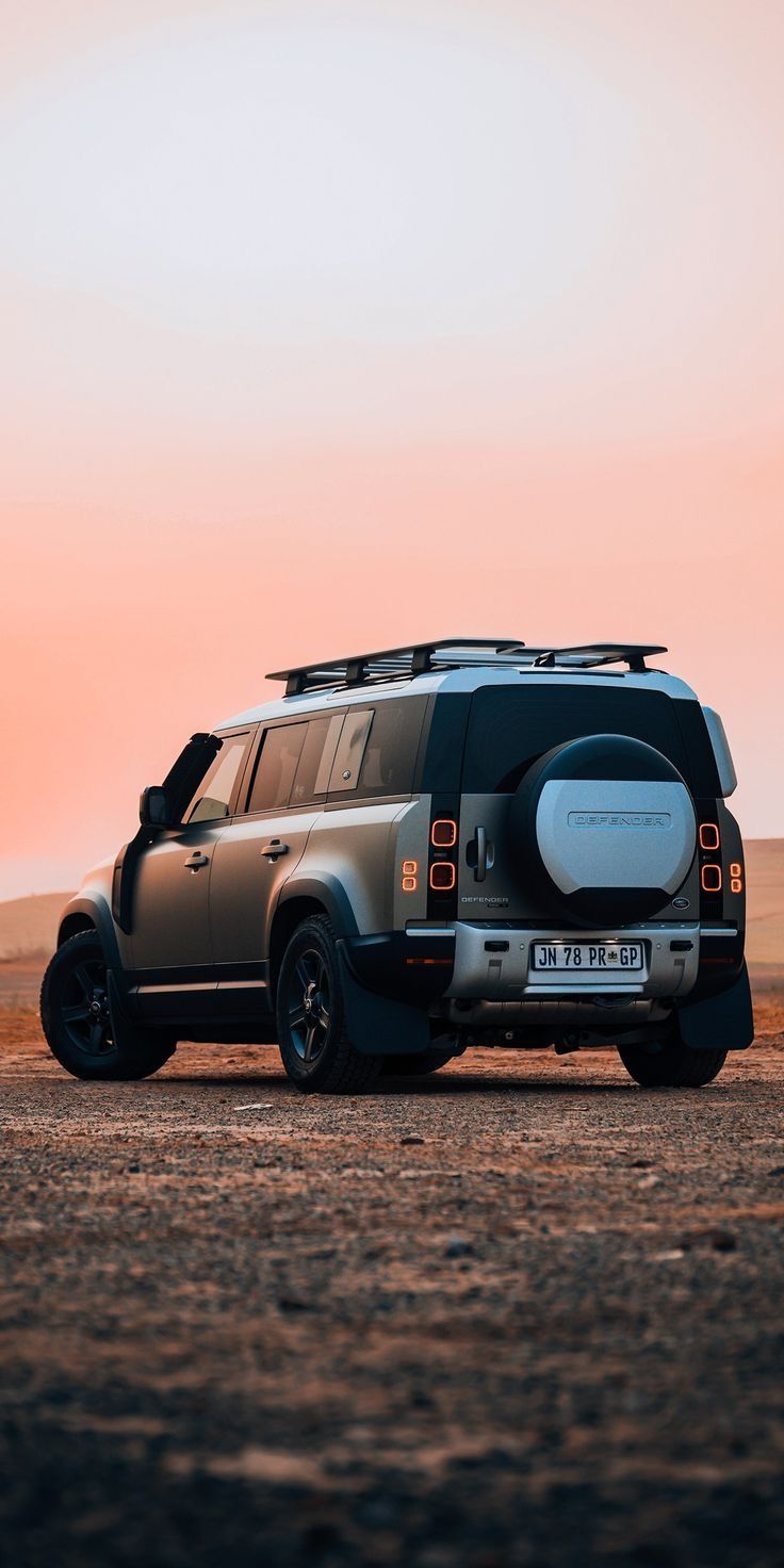 an suv is parked in the desert at sunset