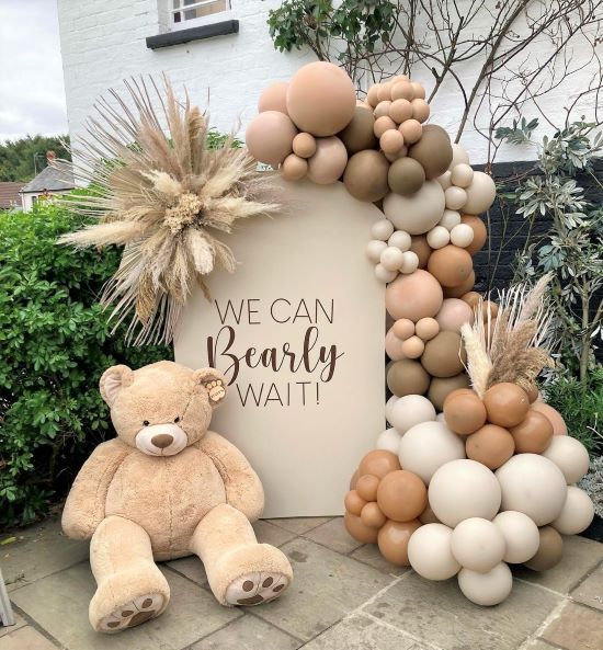 a teddy bear sitting in front of a sign that says we can bearly wait