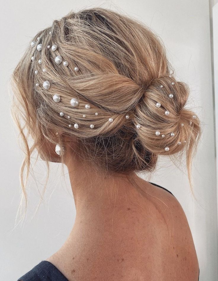 a woman with her hair in a low bun and pearls on the top of her head